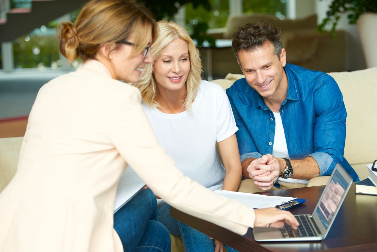 A woman showing two men how to use a laptop.