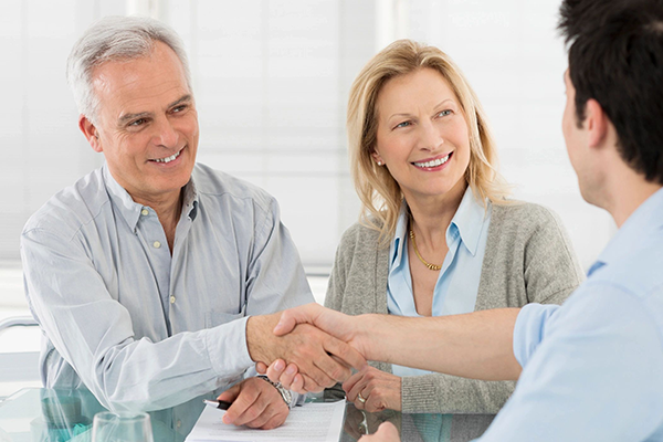 A man and woman shaking hands over a table.